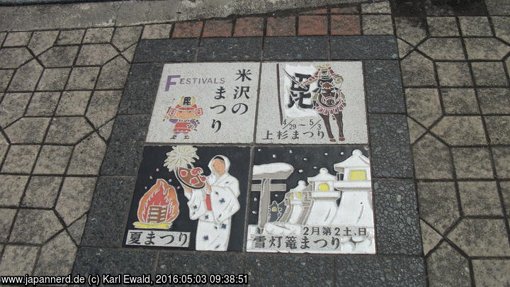 Yonezawa: Pflastersteine beim Bahnhof weisen auf Matsuri hin, rechts oben das Uesugi Matsuri 29.4.-3.5.
