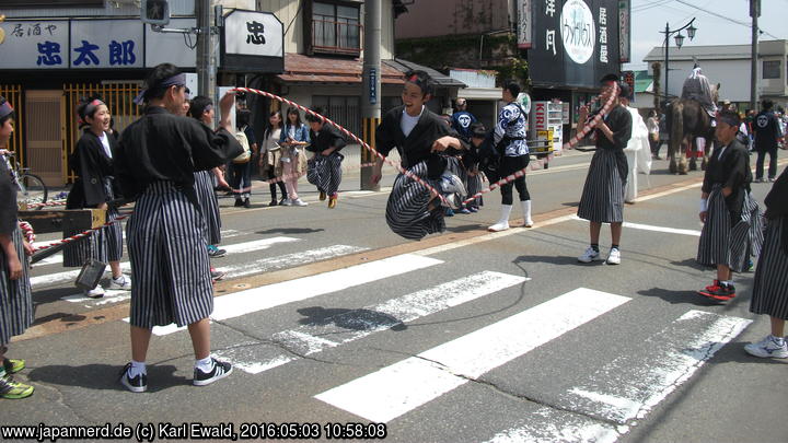 Yonezawa, Uesugi Matsuri: die Kinder nutzen im Stillstand das Zugseil vor einem Mikoshi zum Seilspringen
