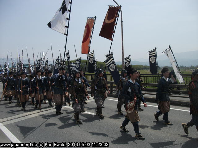 Yonezawa, Uesugi Matsuri: dem General (rechts abgeschnitten) folgen Schwertkämpfer mit Helm, dann Fußvolk mit Speeren, und es gibt ganz viele Fahnen
