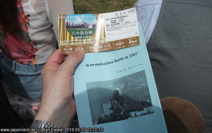 Yonezawa, Uesugi Matsuri: Die Platzkarte umfasst (für mich auf englisch) auch ein Skript für das dargestellte Geschehen, eine Flasche Wasser, ein Kissen und ein Tuch.
